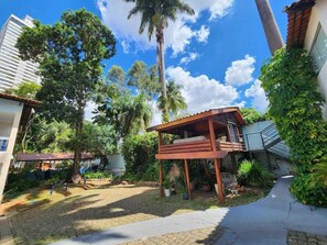 A courtyard with a wooden pergola, a palm tree, and a brick pathway. - Pousada Serras De Goyaz (Goiânia)