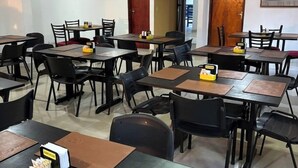 A dining area with multiple tables and chairs, equipped with placemats and condiments. - Pousada Serras De Goyaz (Goiânia)