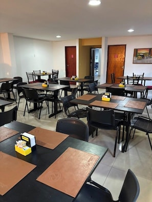 A dining area with multiple tables and chairs, equipped with placemats and condiments. - Pousada Serras De Goyaz (Goiânia)