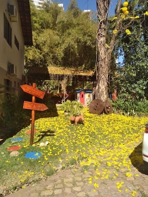 A garden with a directional sign, a tree, and a small structure.