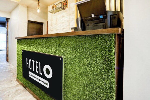 A hotel reception desk with a sign indicating it is a company-serviced hotel.