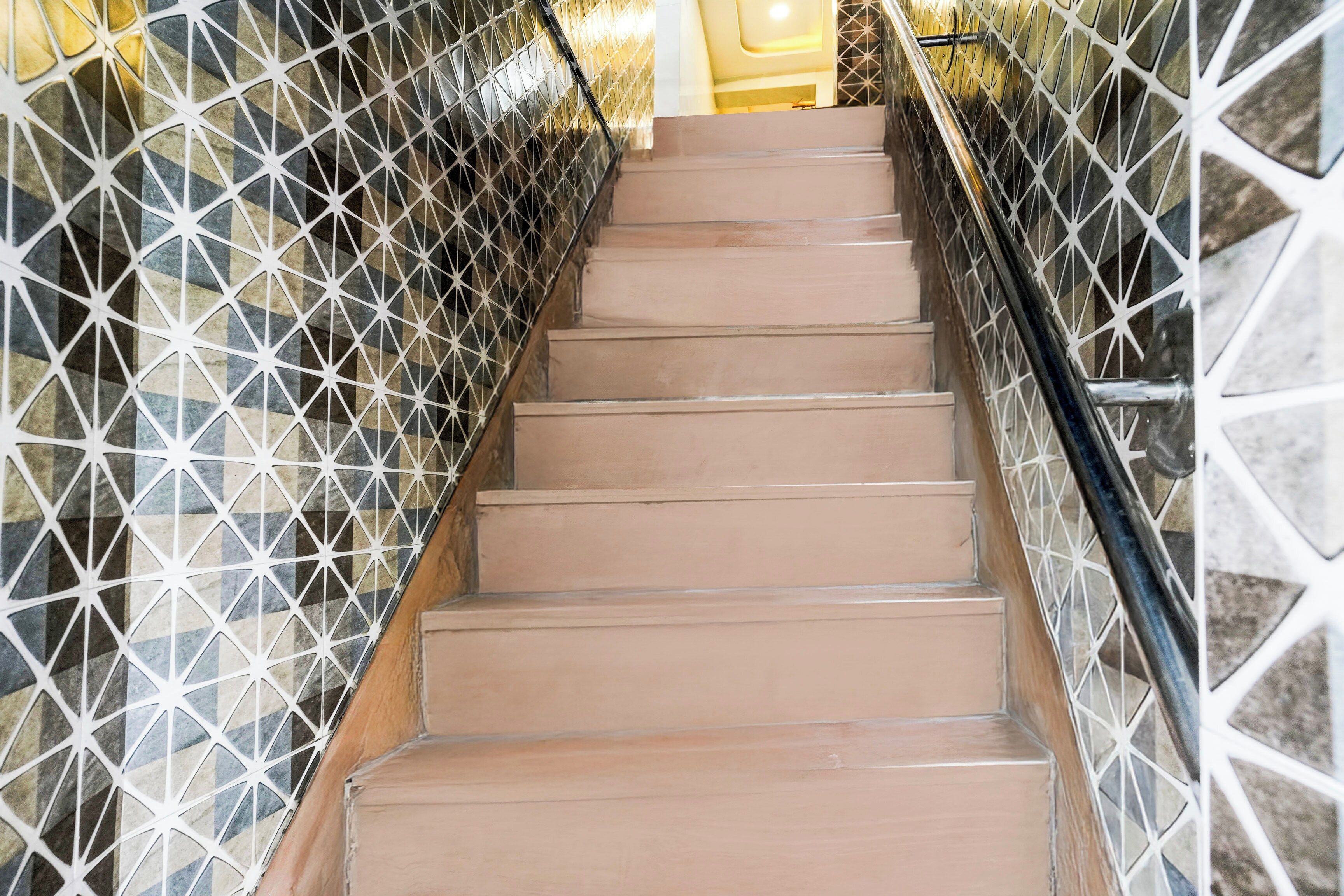 A staircase with a geometric patterned railing and a plain wall.