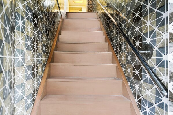 A staircase with a geometric patterned wall on either side and a metal handrail.