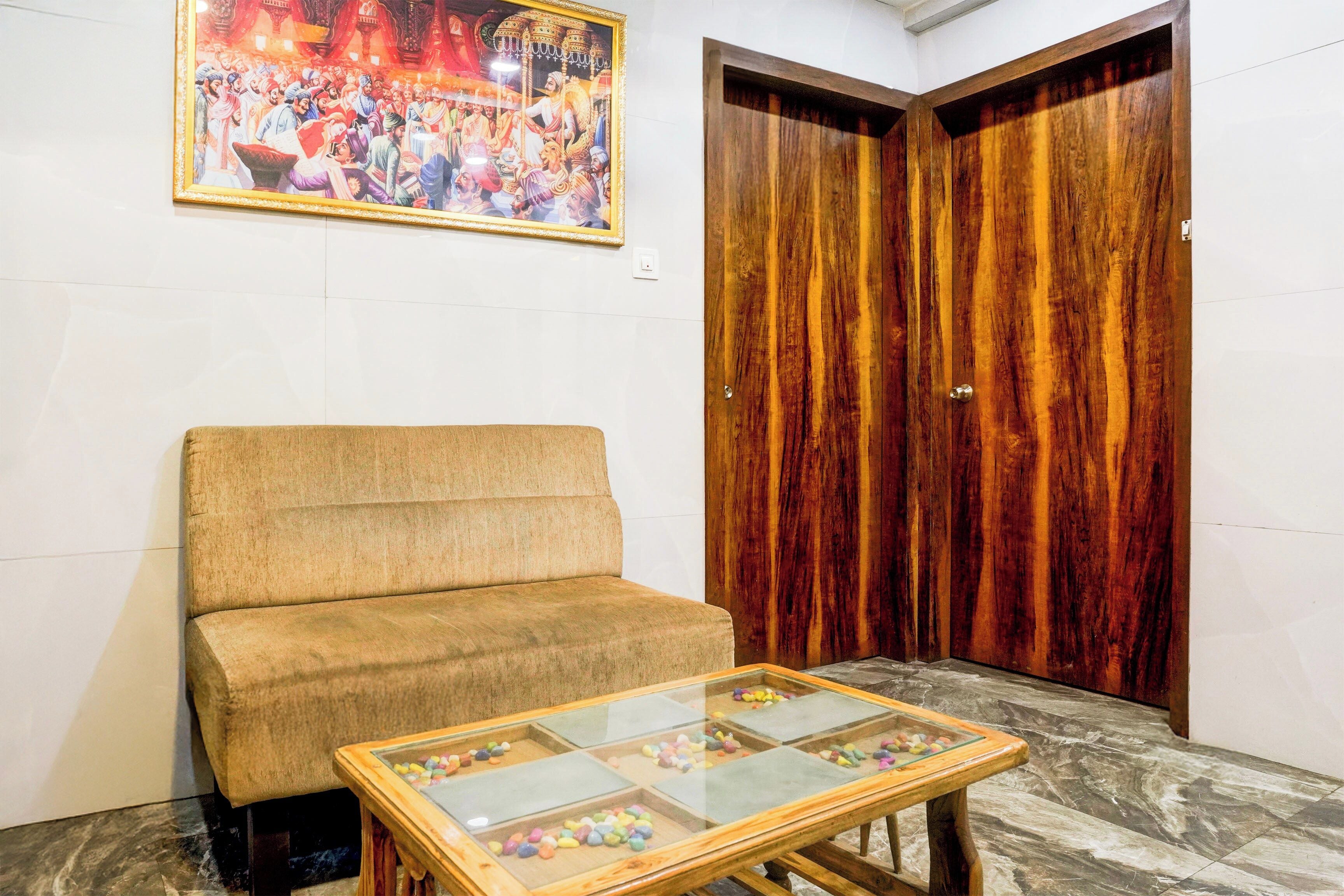 A room with a sofa, a glass-top table with candies, and a wooden door.