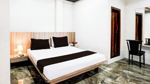 A hotel room with a bed, bedside table, lamp, and a chair. - Hotel O Dombivali Formerly PK Lodging (Kalyan)