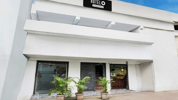 A modern hotel building with a sign indicating it is company-serviced. There are three large windows on the ground floor, and potted plants are placed in front. - Hotel O Dombivali Formerly PK Lodging (Kalyan)