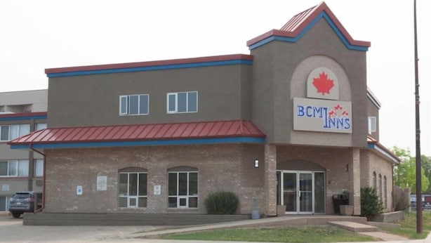 A two-story building with a red roof and a sign for BCMT Inns. - Bcm Inns Fort Mcmurray - Downtown (Fort McMurray)