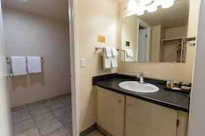 Un baño con lavamanos, espejo y toallero.