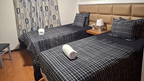 A hotel room with two beds, a nightstand, a lamp, and a curtain. - Apartment 'Azenha View' with Sea View, Balcony and Wi-Fi (Caniço)