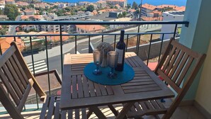 A balcony with a table and chairs, overlooking a coastal town with buildings and the sea. - Apartment 'Azenha View' with Sea View, Balcony and Wi-Fi (Caniço)