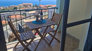 A balcony with a table, chairs, and a bottle of wine. - Apartment 'Azenha View' with Sea View, Balcony and Wi-Fi (Caniço)