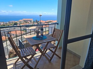 A balcony with a table, chairs, and a bottle of wine. - Apartment 'Azenha View' with Sea View, Balcony and Wi-Fi (Caniço)