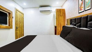 Ein Hotelzimmer mit einem Bett, einer Holztür, einer Klimaanlage und einem gerahmten Bild an der Wand.