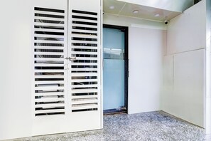 Un pasillo con una puerta blanca, una puerta de cristal e iluminación empotrada en el techo.