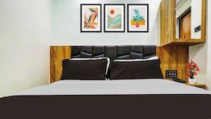 Ein Bett mit Holz-Kopfstück, ein Nachttisch mit Telefon und eine Wand mit drei gerahmten Kunstwerken.
