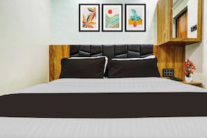 Ein Bett mit Holz-Kopfstück, ein Nachttisch mit Telefon und eine Wand mit drei gerahmten Kunstwerken.