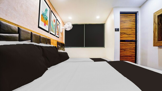 Ein Hotelzimmer mit einem großen Bett, einem Nachttisch, einem Wandventilator und einer Tür mit einem Holzpaneel.