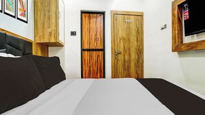Ein Schlafzimmer mit einem Bett, zwei Holztüren, einem Fernseher und einem an der Wand befestigten Lichtschalter.