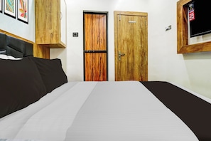 Ein Schlafzimmer mit einem Bett, zwei Holztüren, einem Fernseher und einem an der Wand befestigten Lichtschalter.