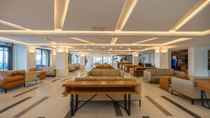 Eine geräumige Lobby mit einer zentralen Sitzecke, mehreren Sofas und einem langen Holztisch.