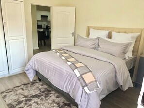 A bedroom with a bed, a headboard, and a bedside table.