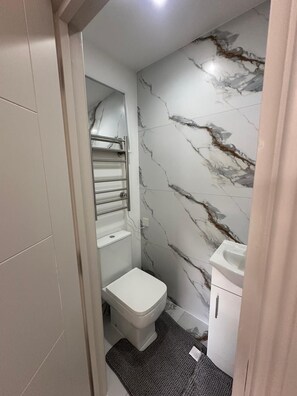 A small bathroom with a toilet, a towel rack, and a sink. - Apartment Sleeps 2 With Shared Kitchen Near City (London)