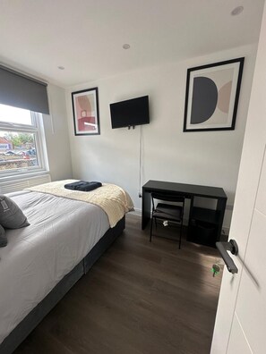 A bedroom with a bed, a desk, a chair, and two framed artworks on the wall. - Apartment Sleeps 2 With Shared Kitchen Near City (London)