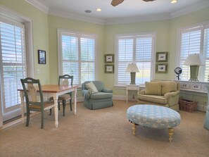 A room with a dining table, chairs, a sofa, a loveseat, a small side table with a lamp, and a window with blinds. - Palmetto Cove - Oceanfront with Elevator and Awesome Deck (Pawleys Island)