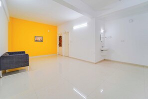 A room with a yellow wall, a white door, and a white sink. - Collection O Kochi Mary Varkeys Park (Kanayannur)
