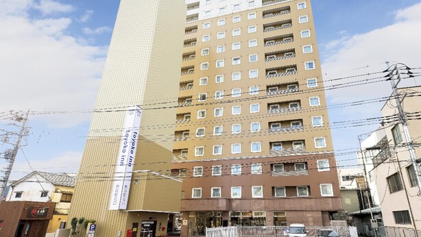 Ett hotell med flera våningar, med en tydlig skylt som visar namnet ”Toyoko Inn” och en webbadress.