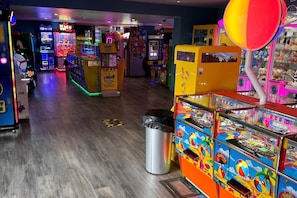 Eine Indoor-Spielhalle mit verschiedenen Spielautomaten, darunter ein Ticket-Löseautomat und ein Krabbenklauenautomat.