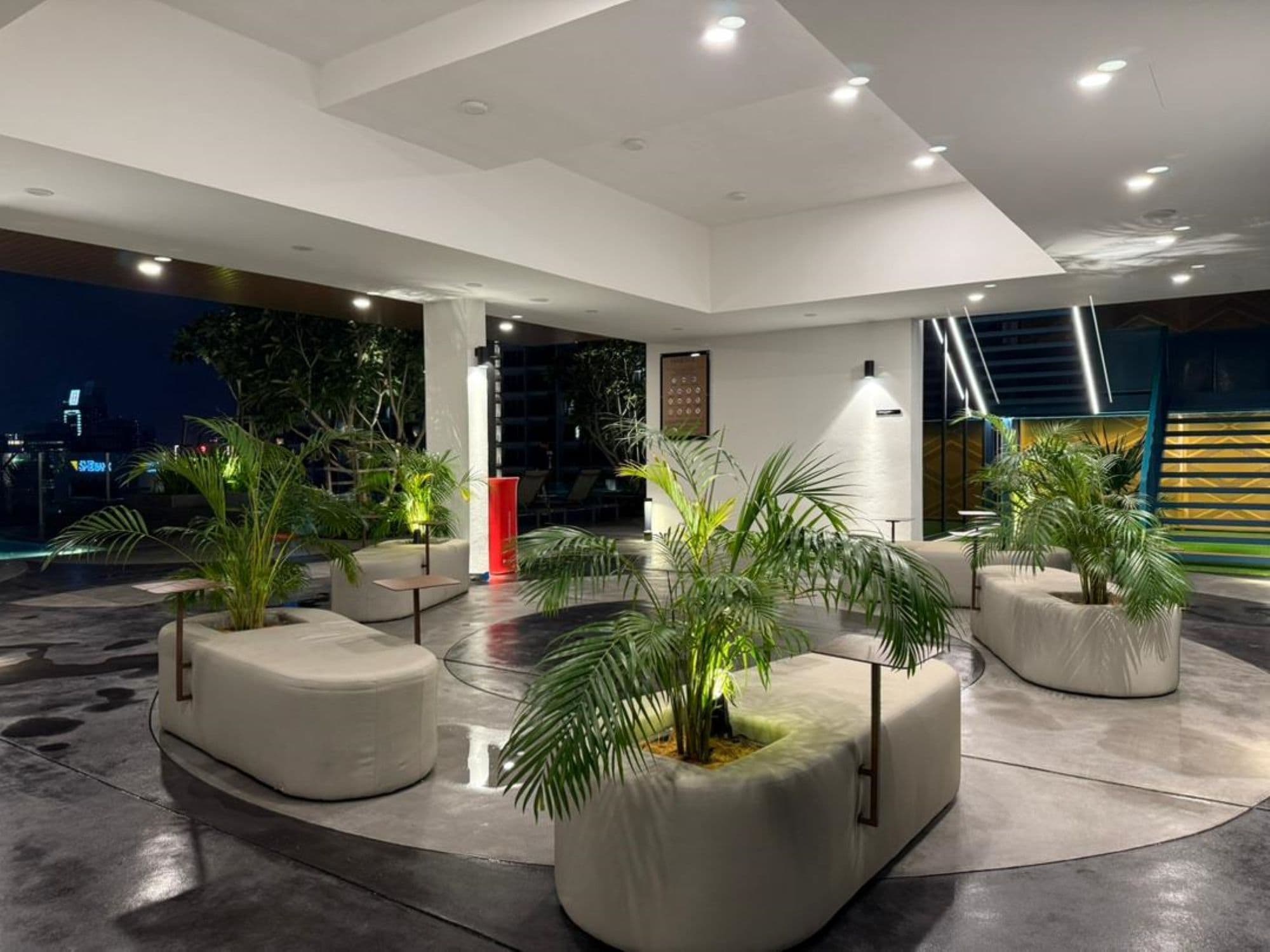 Un espacio interior moderno con zonas de estar y plantas en macetas.