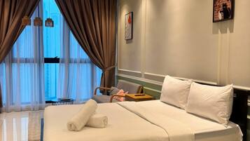 Una habitación de hotel con una cama grande, un ventilador de techo, una ventana con cortinas y un cuadro en la pared.