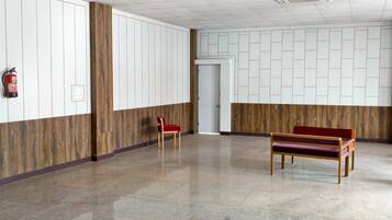 A hallway with a wooden panel wall, a fire extinguisher, a bench, and a door.