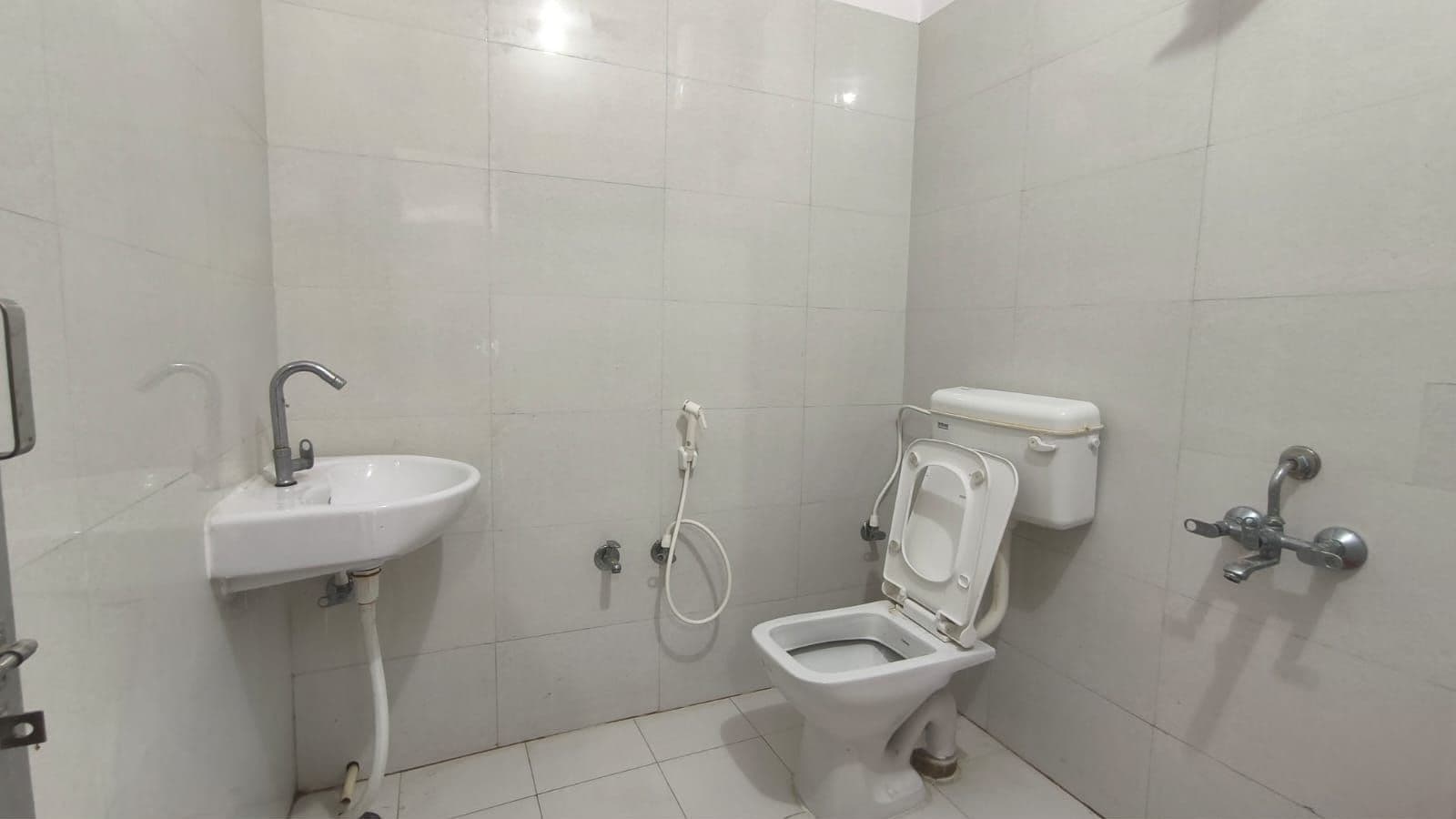A small, clean bathroom with a white sink, toilet, and shower.