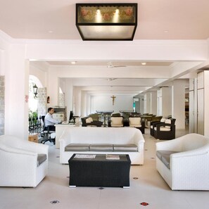 Un vaste espace de vie comprenant un canapé blanc, deux fauteuils, une table basse et un coin repas avec des chaises et une table.