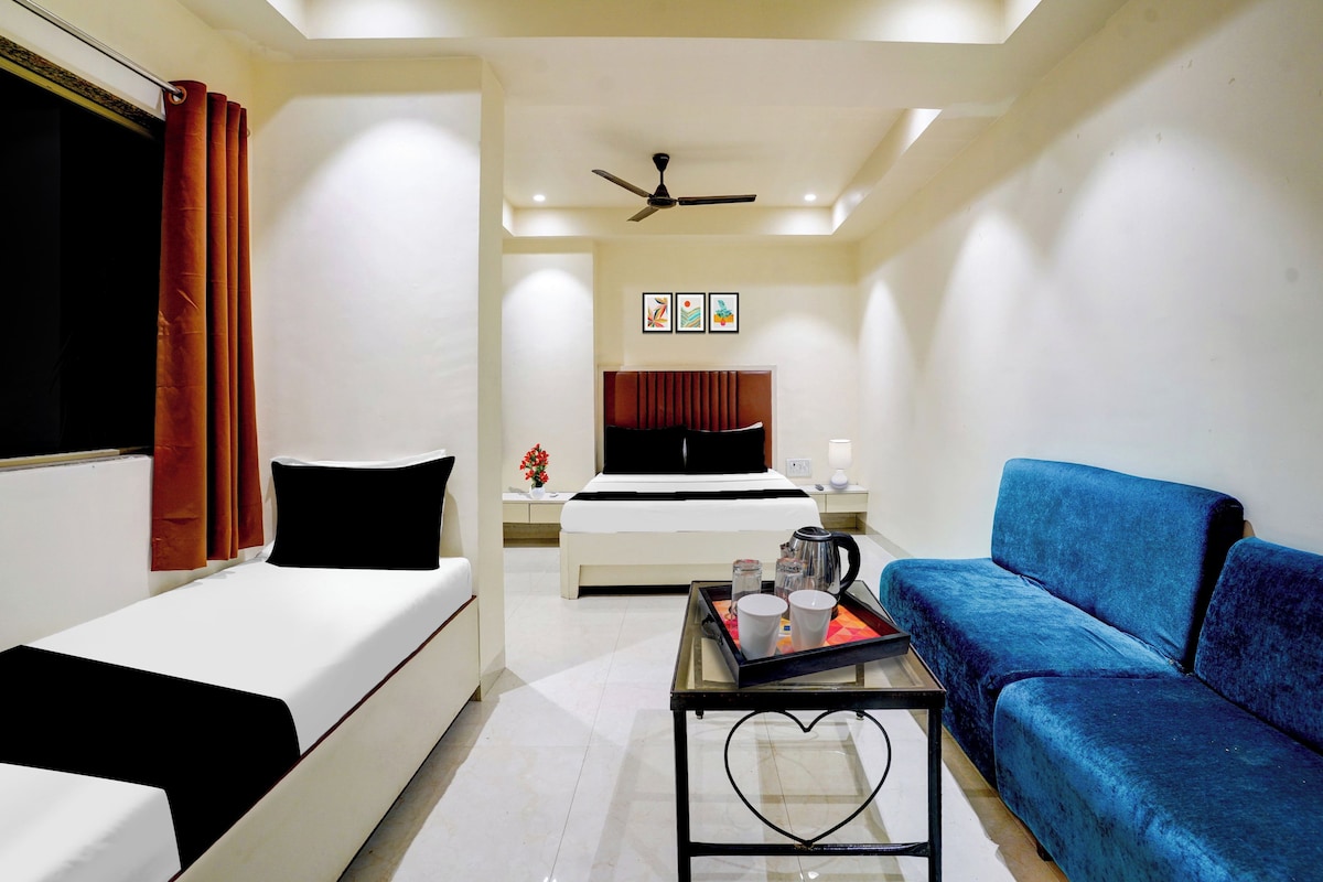 A hotel room with a bed, a blue sofa, a coffee table, and a ceiling fan.