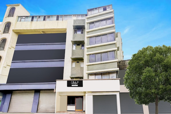 A multi-story building with a flat facade, large windows, and a sign indicating a company service. - O Ulhasnagar Formerly Hotel Derby (Mumbai)