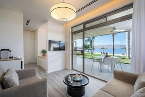A modern living room with a large sliding glass door leading to an outdoor patio with a view of the sea. - Kibbutz Ein Gev (Tiberias)