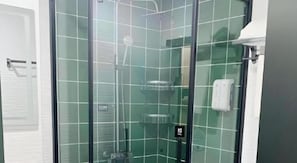Ein Duschbereich mit Glaswänden, Bedienfeld, Handtuchspender und Handtrockner.