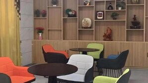 A room with a variety of seating options including chairs and a table, a wooden shelving unit with decorative items, and a curtain on the left side. - Greentree Inn Express Xuzhou Pizhou Tiefu Town Bus Station (Xuzhou)
