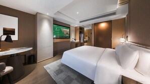 A modern hotel room with a bed, desk, chair, and a TV displaying a room service menu. - Atour Hotel (Lanzhou)