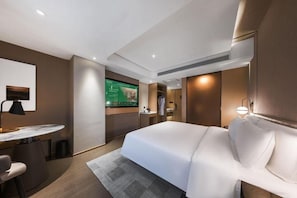 A modern hotel room with a bed, desk, chair, and a TV displaying a room service menu. - Atour Hotel (Lanzhou)
