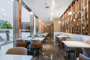 A modern restaurant interior with marble flooring, multiple tables and chairs, and large windows allowing natural light. - Atour Hotel (Lanzhou)