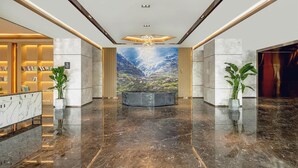 A hotel lobby with a marble floor, a reception desk, a large mural, and potted plants. - Atour Hotel (Lanzhou)