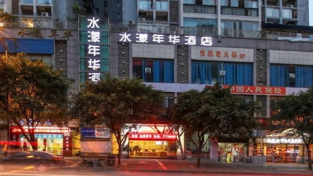 Un hotel de varios pisos, con un letrero destacado que dice 'Water Year Year Old Hotel' y un cartel de seguros visible.