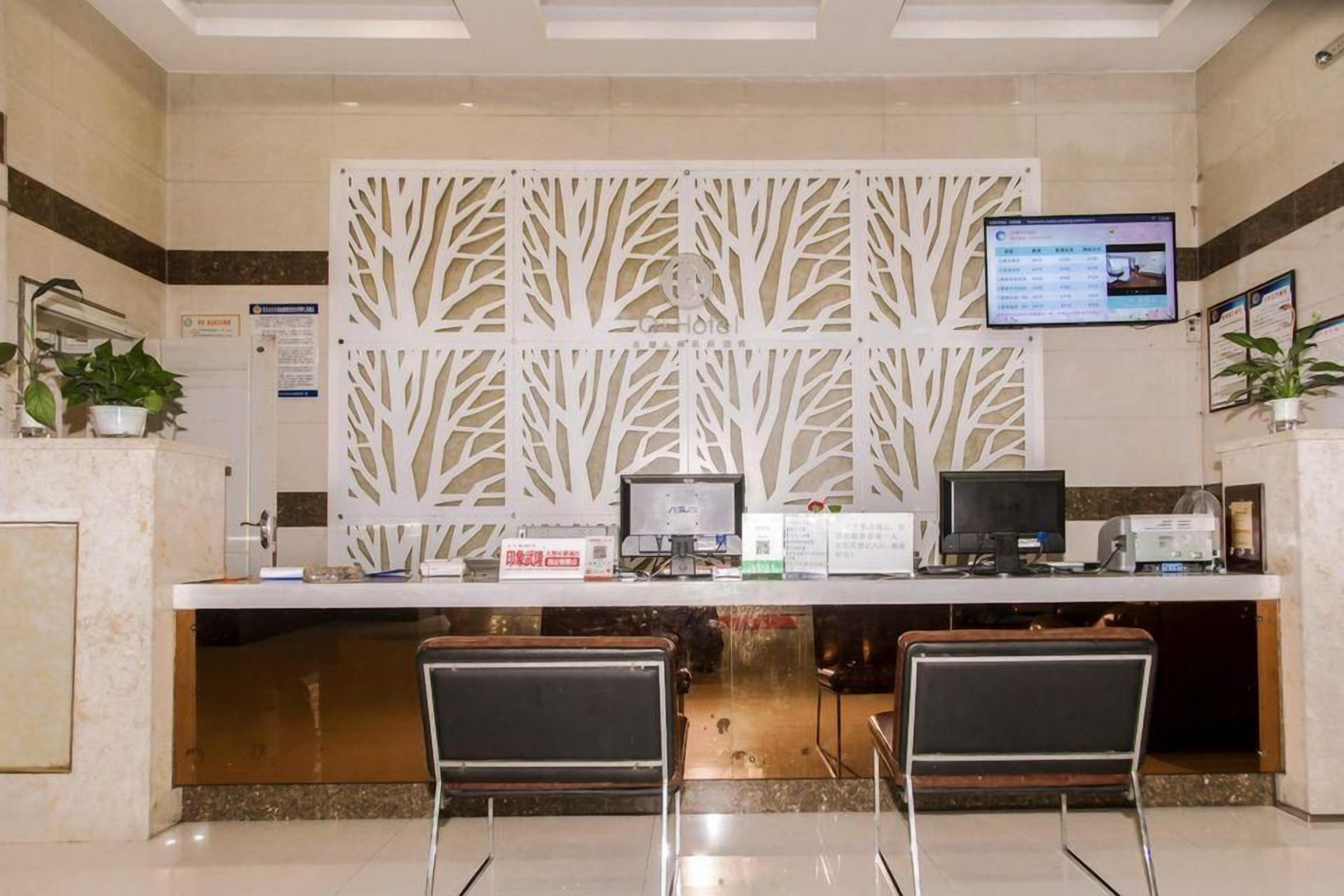 A reception desk with two computer monitors, a digital screen, and a decorative white panel.