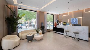 A modern hotel lobby with a reception desk, seating area, and large windows. - 7 Days Inn (Jiuquan)