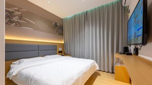 A hotel room with a large bed, a flat-screen TV, a wooden desk, and a curtain. - 7 Days Inn (Jiuquan)