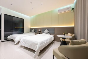 A hotel room with two beds, a sofa, a small table, and an air conditioning unit. - 7 Days Inn (Jiuquan)
